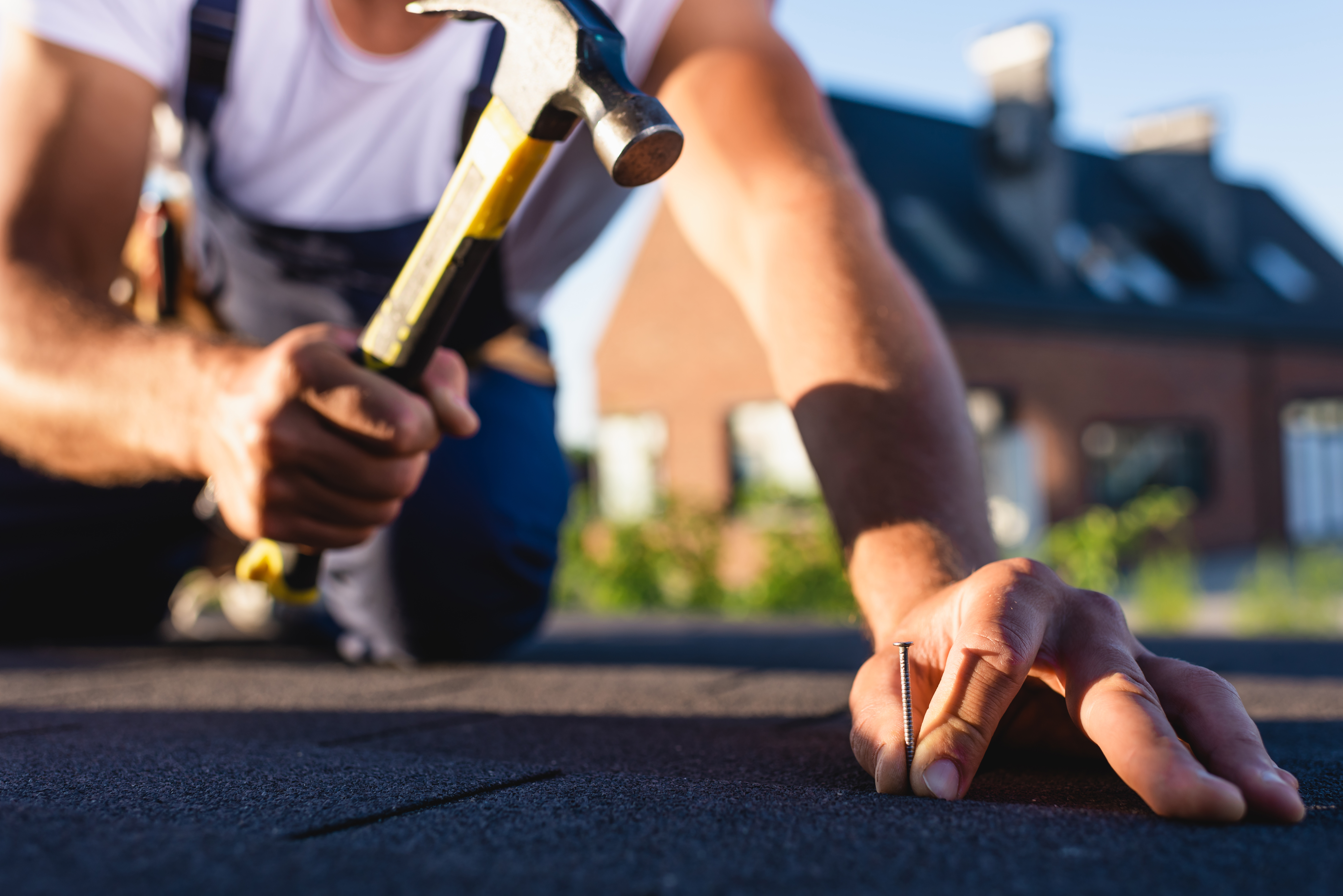 Close-up of professional roofer with hammer and nails